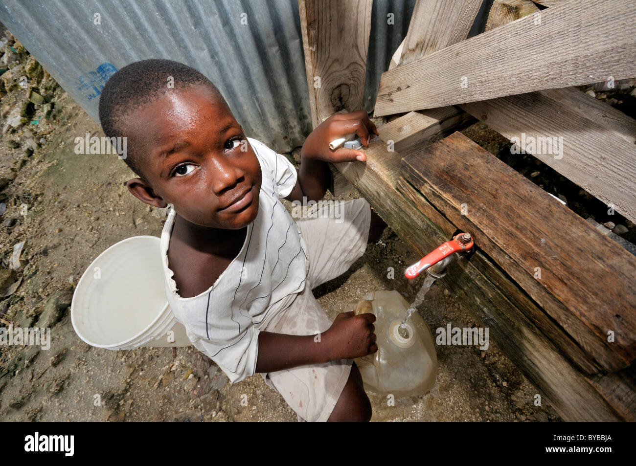 Acqua potabile impianto di trattamento in una delle baraccopoli, ragazzo il riempimento di acqua pulita in un jerrican, , Haiti, dei Caraibi e America centrale Foto Stock