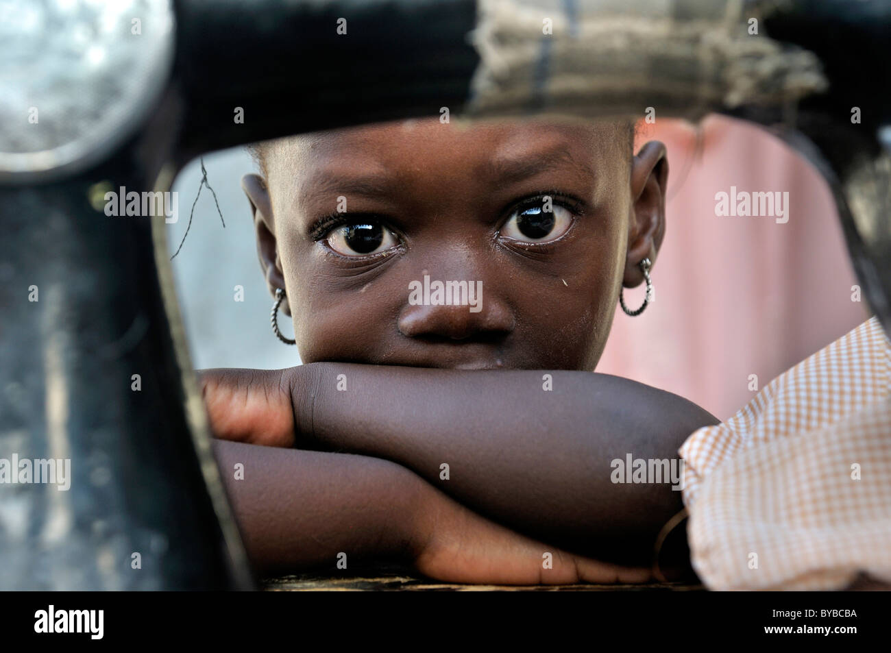 Bambina nascosto dietro un vecchio meccanico della macchina da cucire, camp per le vittime del gennaio 2010 terremoto Foto Stock