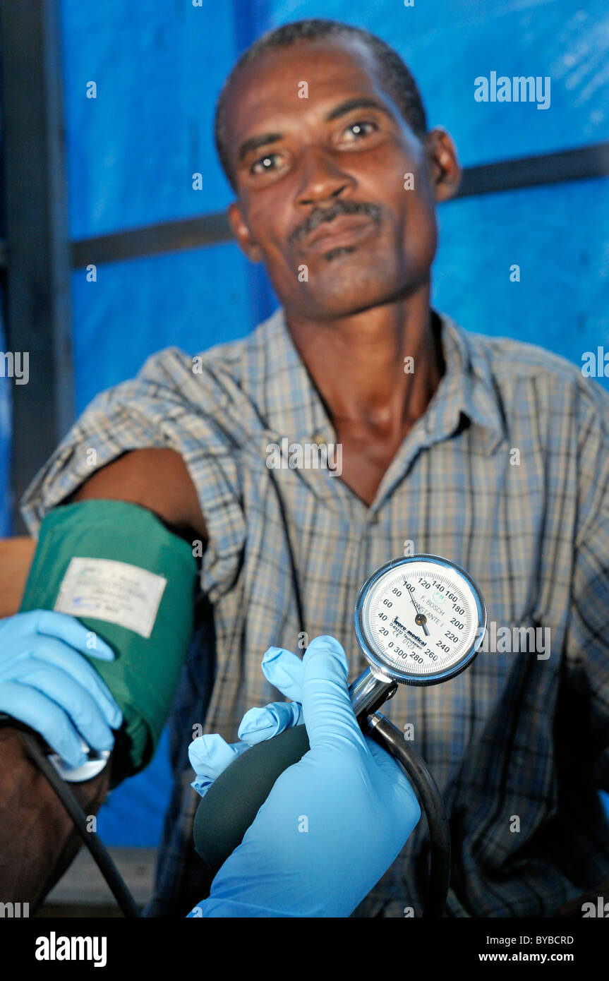 L'uomo con la sua pressione del sangue presi in ospedale mobile di un rilievo organizzazione, Léogâne, Haiti, dei Caraibi e America centrale Foto Stock