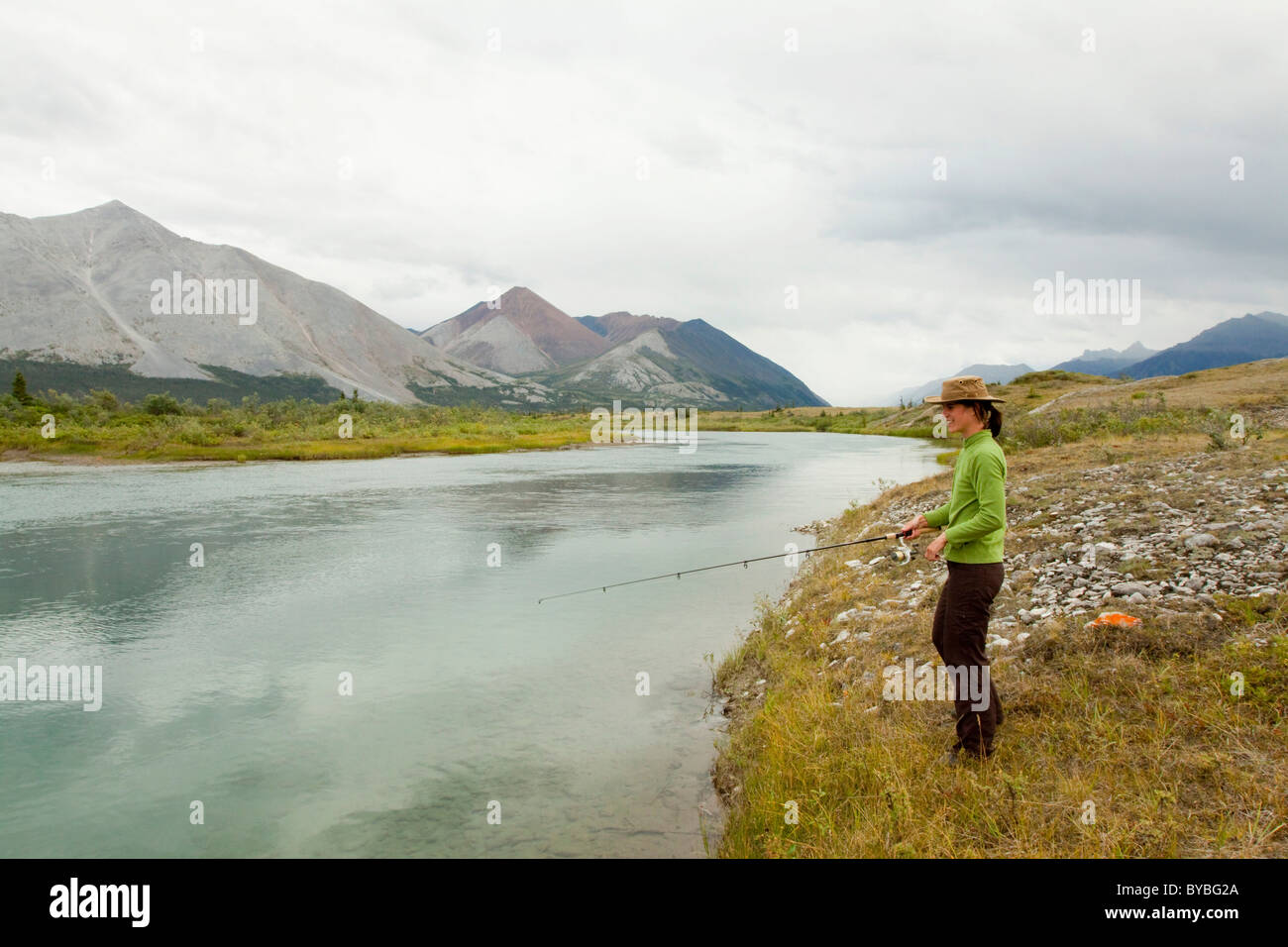 Giovane donna pesca, Wind River, Mackenzie montagne dietro, Yukon Territory, Canada Foto Stock