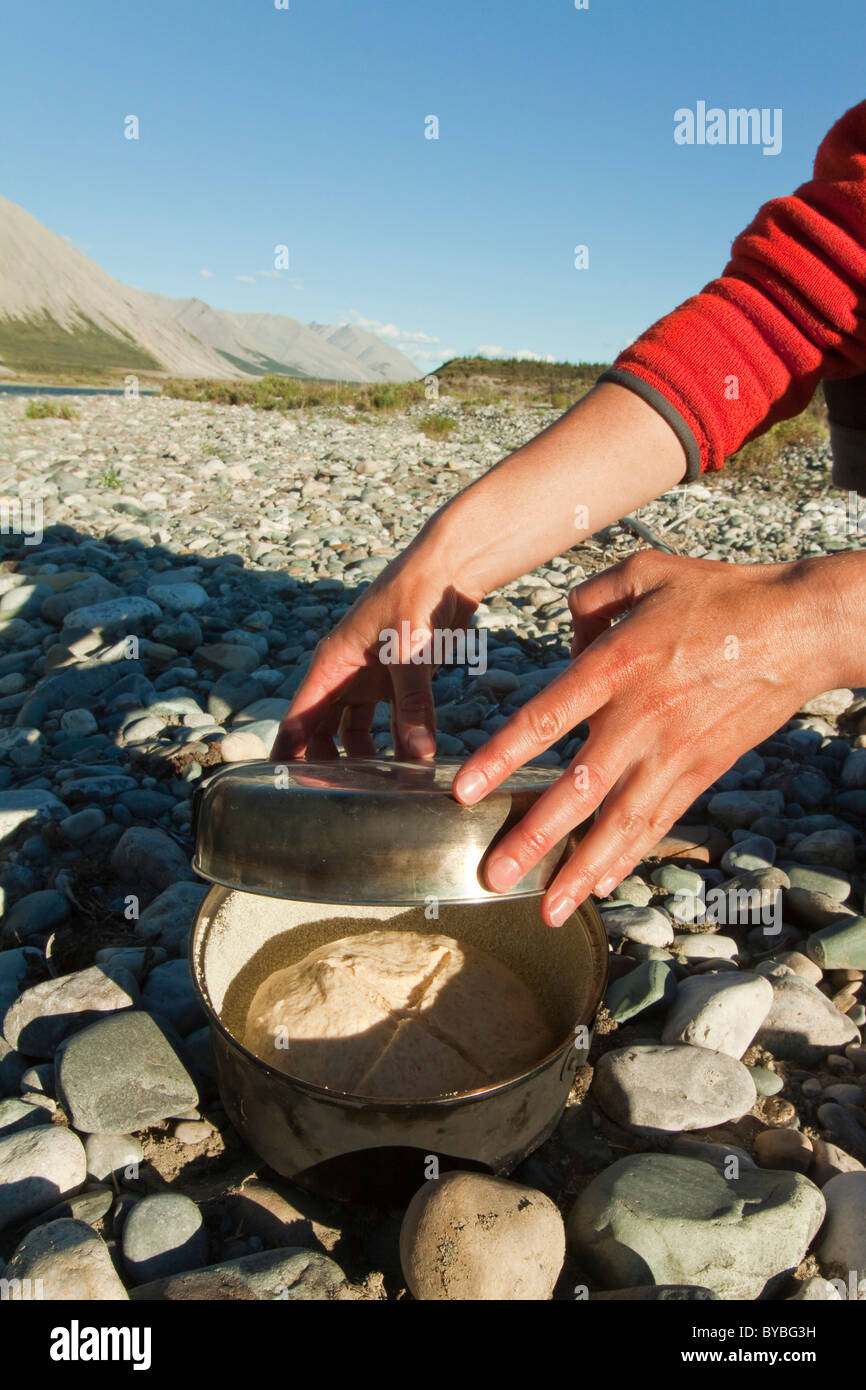La cottura del pane su un fuoco di campo, coprendo la piccola la pentola con un coperchio, grill, camping, Wind River, Yukon Territory, Canada Foto Stock