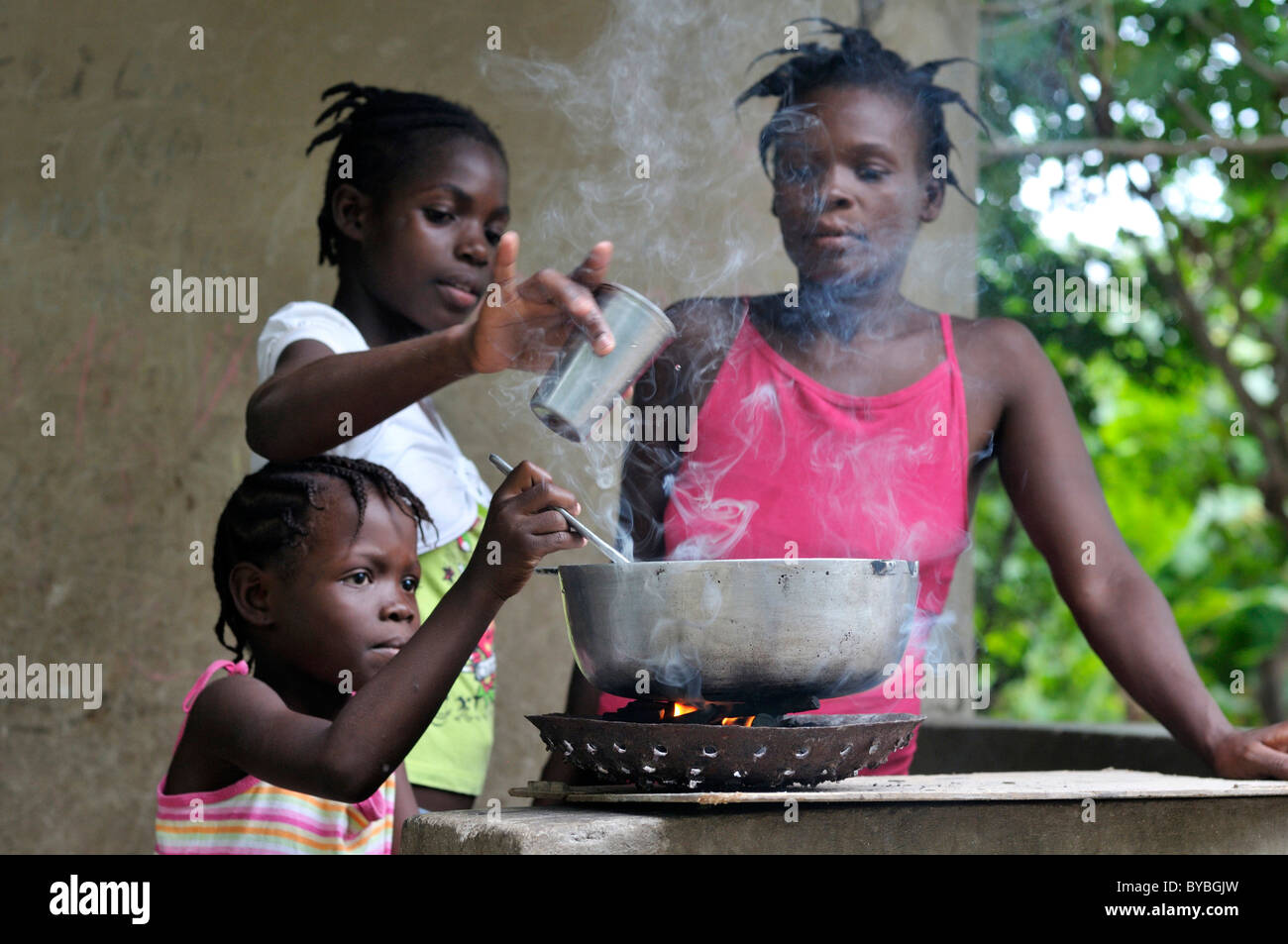 La madre e le figlie per la cottura su un braciere, cabaret, Haiti, dei Caraibi e America centrale Foto Stock