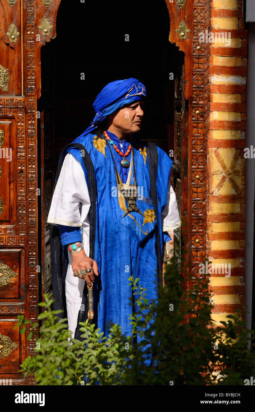 Profilo della tradizionale blu abbigliamento costume di Berber Taureg man  standing in ornati in legno intagliato porta nella medina di Marrakech  marocco Foto stock - Alamy