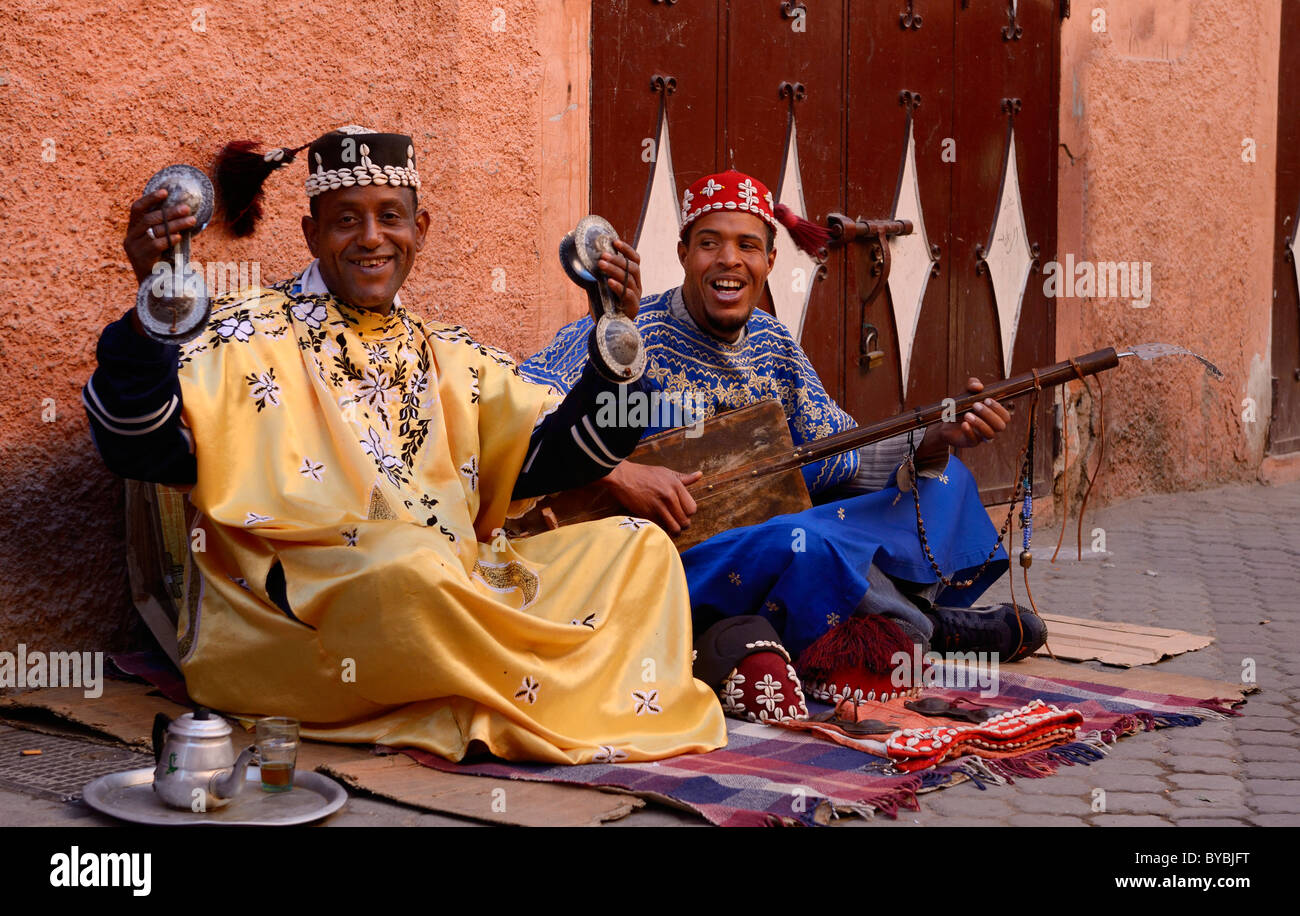 Felice coppia di gnawa street musicians playing hajhuj e krakeb e cantare in Marrakech con brandeggio tarboosh nappe marocco Foto Stock