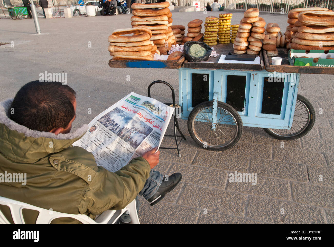 Hawker palestinese la lettura di Al Quds giornale con foto di proteste in Egitto sul lato anteriore della pagina. Gerusalemme la città vecchia Foto Stock