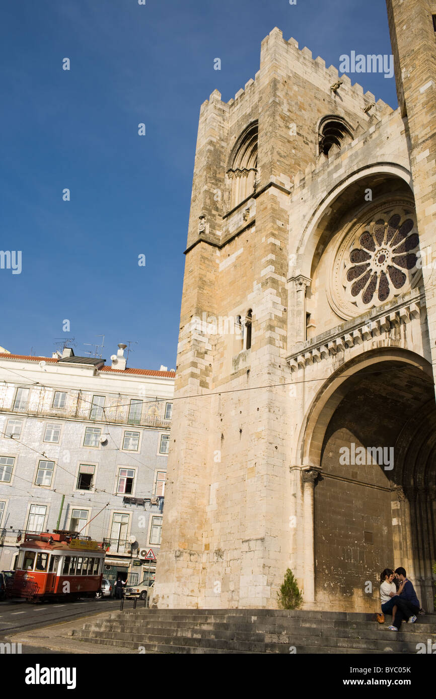 Il Tram 28 passa da baciare coppia al Catedral da Sé, quartiere di Alfama, Lisbona, Portogallo Foto Stock