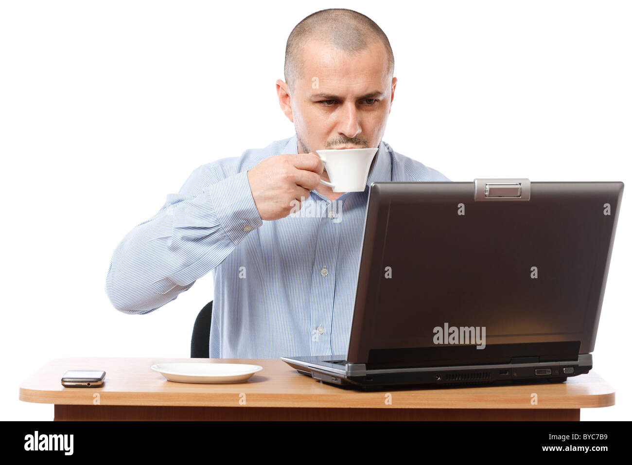 Giovane imprenditore di bere il caffè mentre leggendo qualcosa sul suo computer portatile Foto Stock