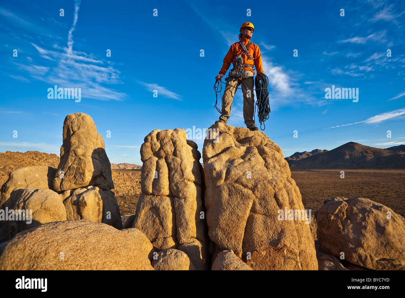 Rocciatore si gode della vista dalla cima di un pinnacolo dopo una salita di successo nel tardo pomeriggio di luce. Foto Stock