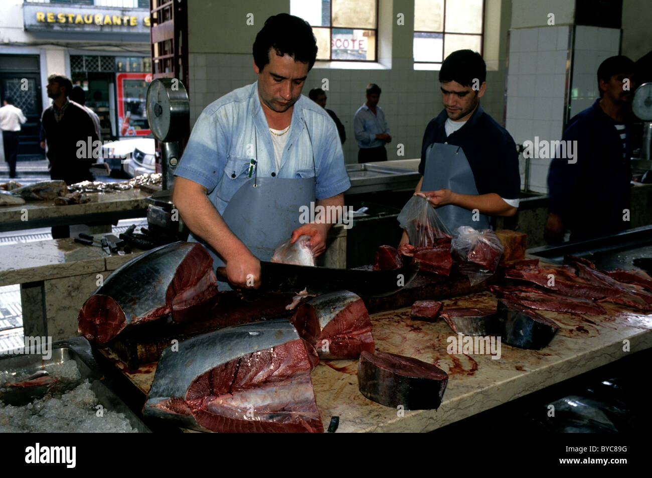 Tritare pescivendolo appena pescati tonni in bistecche su una tavola di marmo a Funchal il Mercado dos Lavradores a Madera Foto Stock