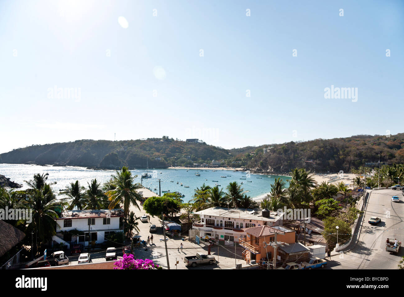 La vista sul molo della città strada principale sulle spiagge contornate di palme & frizzante porto con barche ancorate Puerto Angel dello Stato di Oaxaca Messico Foto Stock