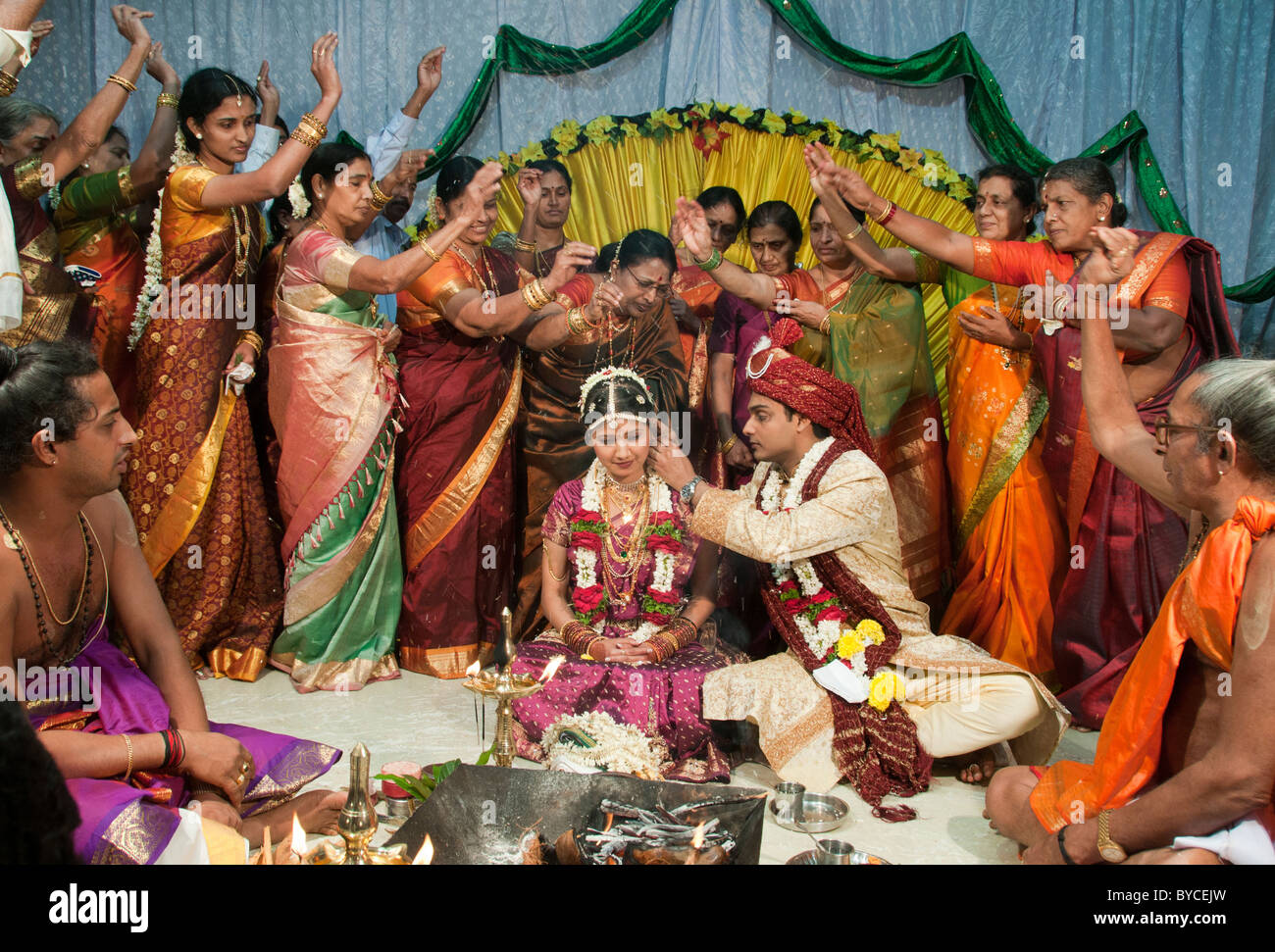 Gli ospiti gettano chicchi di riso oltre gli sposi a simboleggiare abbondanza e buona fortuna a nozze indù in India Foto Stock