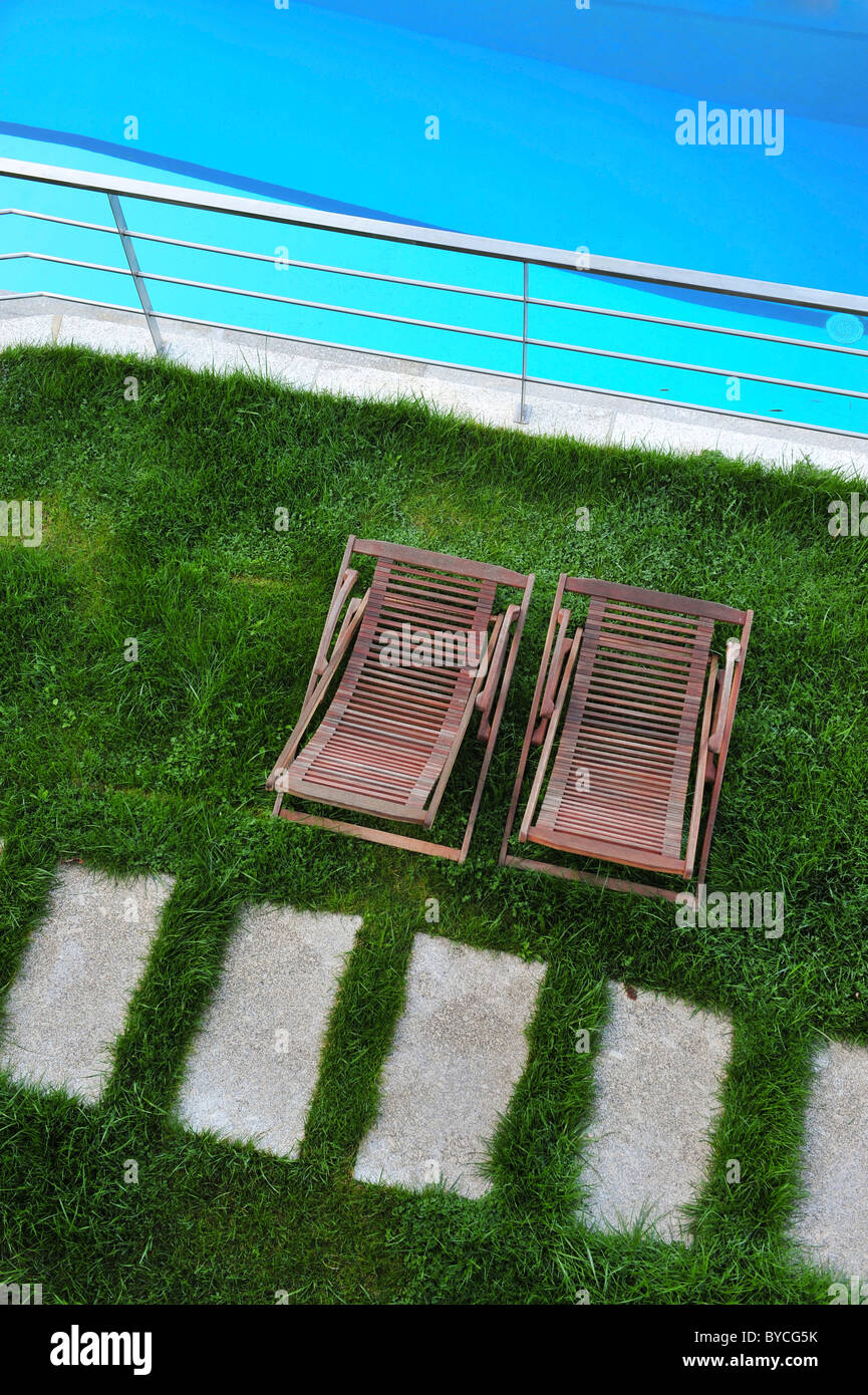Legno sedie a sdraio sul prato accanto alla piscina all'aperto è vista dal di sopra Foto Stock