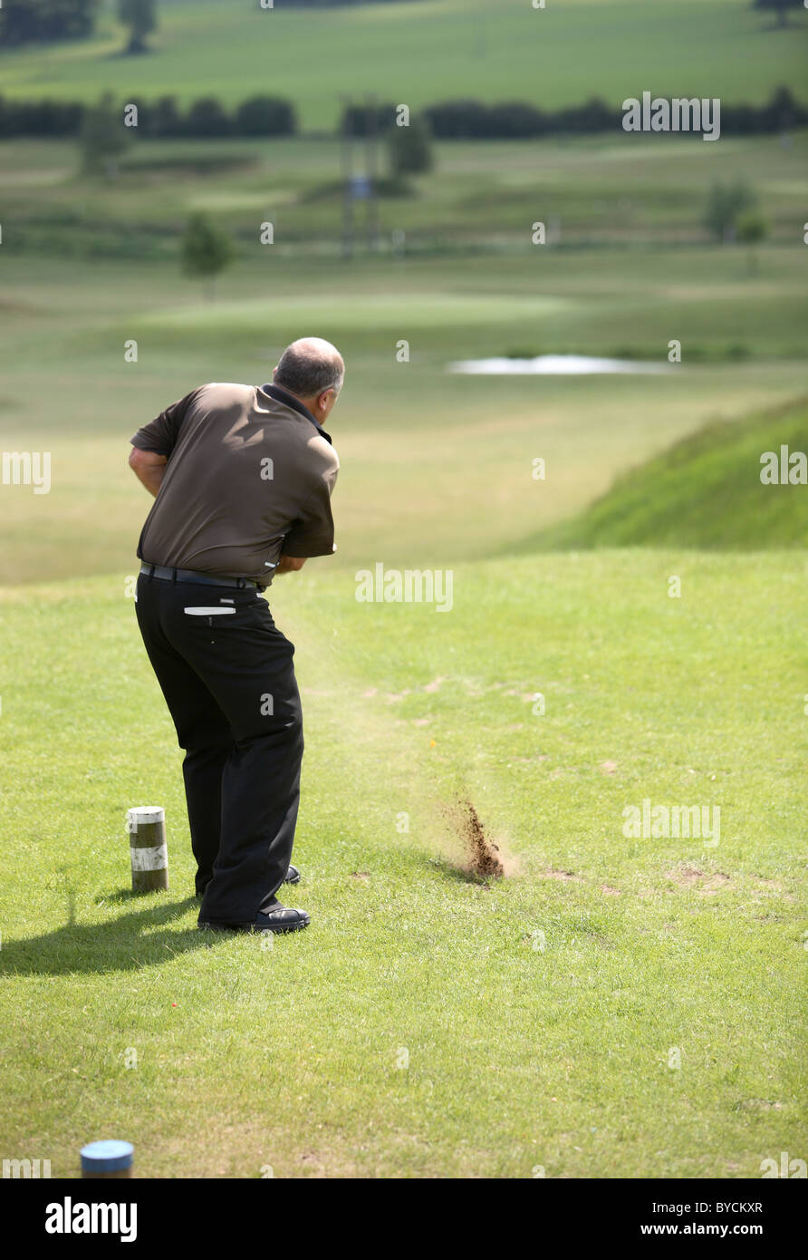 Il Golfer in maglietta marrone di rinvio verso il basso off fairway Foto Stock