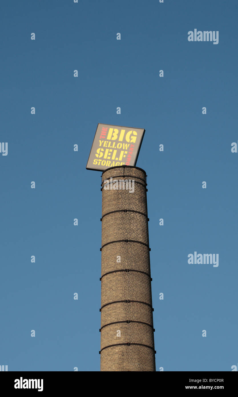 Un 'Grande giallo Self Storage' segno sulla sommità di una ciminiera in mattoni presso la filiale in prua, East London, Regno Unito. Foto Stock