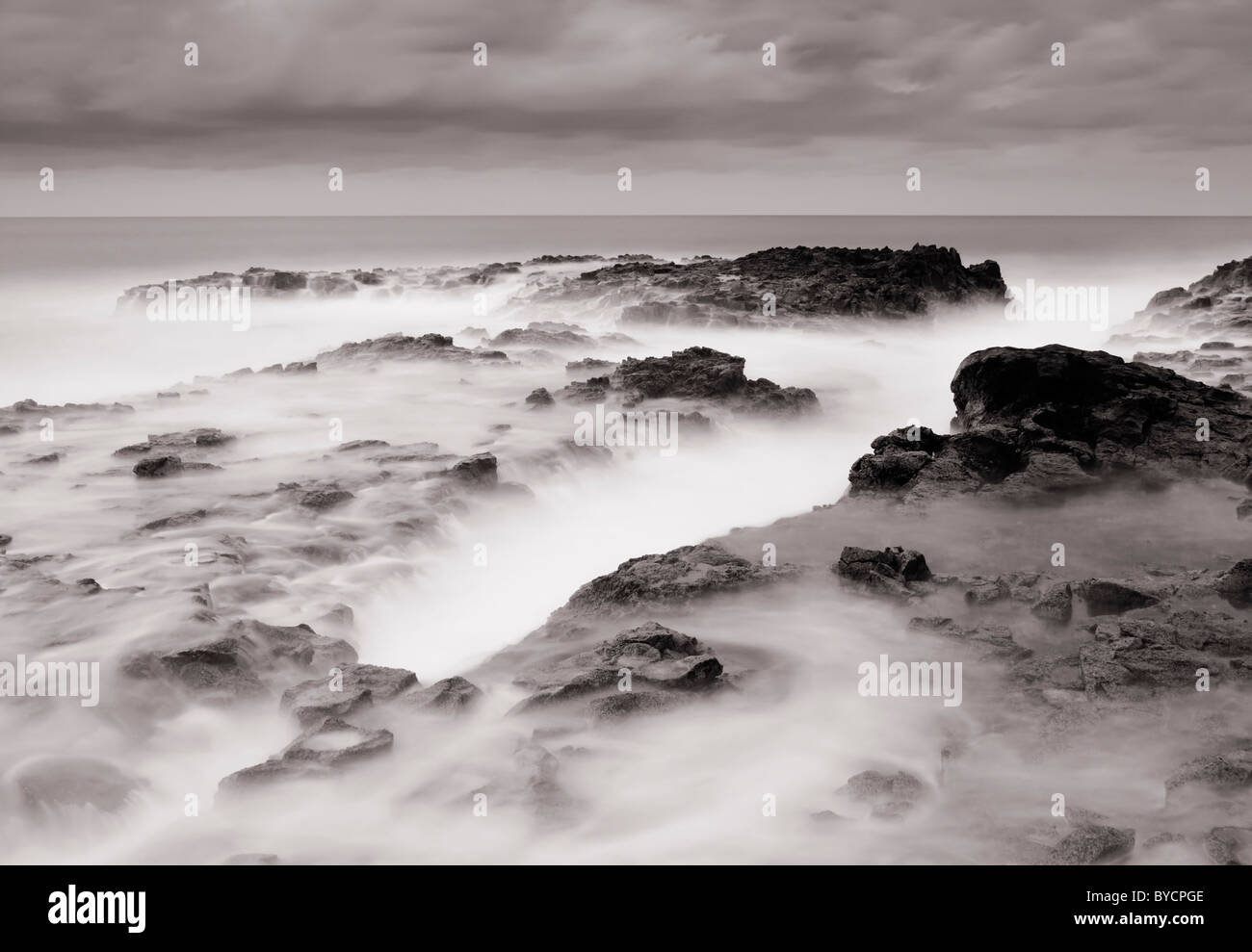 Una lunga esposizione delle onde che si infrangono sulla costa vulcanica Foto Stock