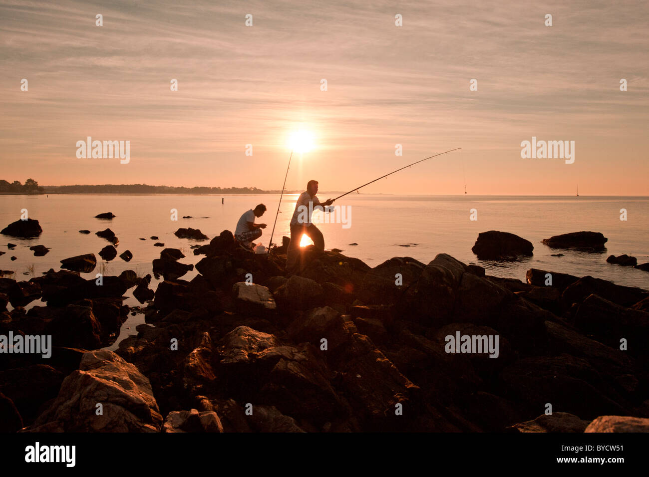 Due uomini la pesca sulle rocce di sunrise, Compo Beach, Westport, Ct. Stati Uniti d'America Foto Stock