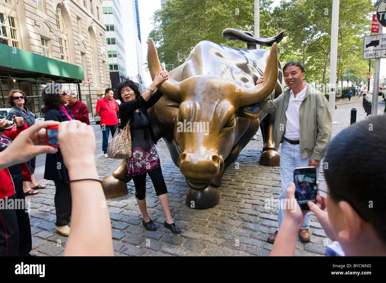 I turisti che posano per una foto oltre la carica bull scultura vicino a Wall Street , New York City, America, STATI UNITI D'AMERICA Foto Stock
