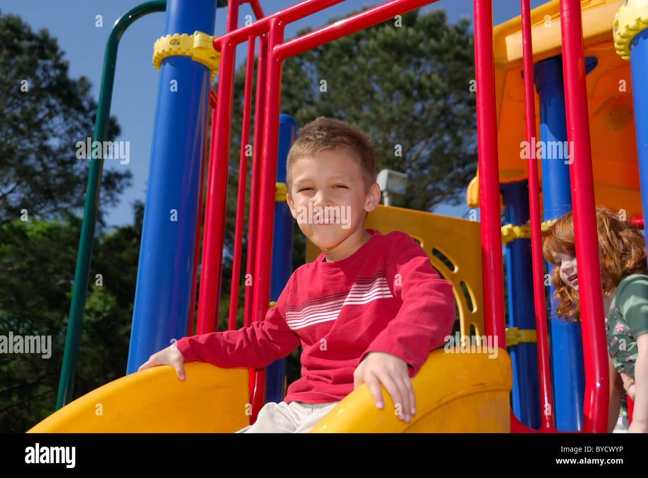 Little Boy giocando su una diapositiva in un parco giochi. Foto Stock