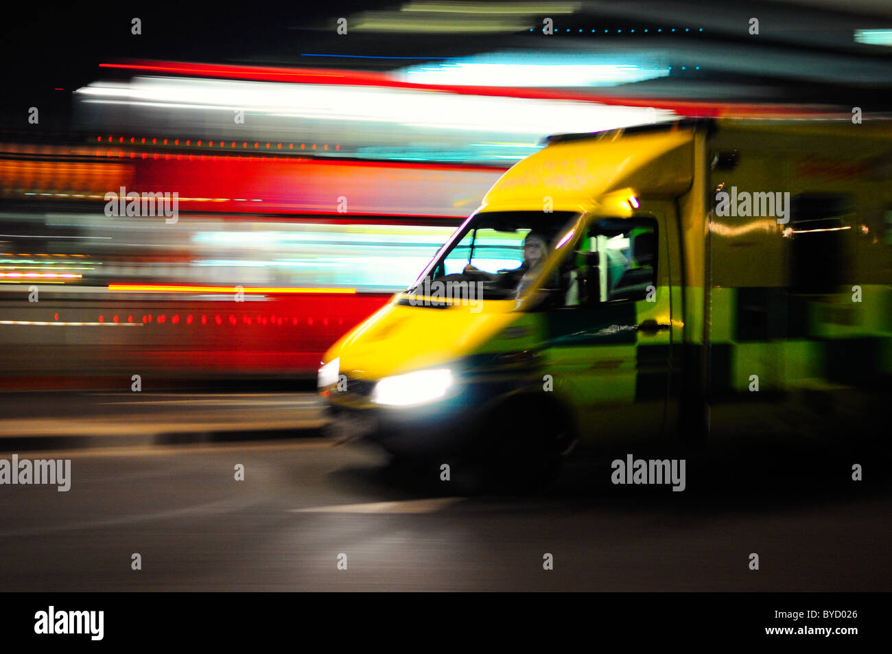 Ambulanza impetuoso passato un bus rosso con motion blur Foto Stock