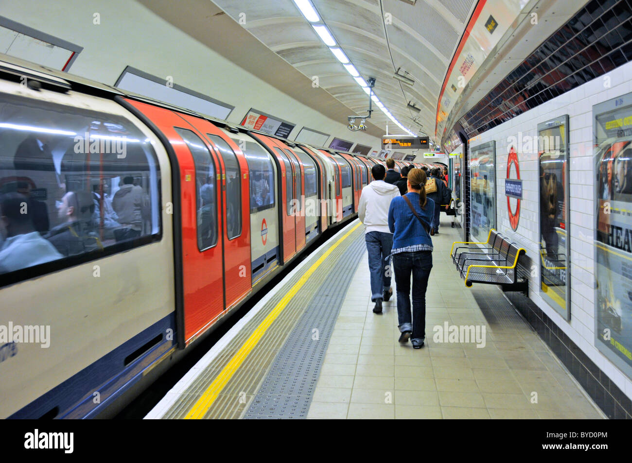 Stazione della metropolitana di Shepherds Bush con il treno della metropolitana Central Line che si sposta via mentre i passeggeri camminano lungo la piattaforma per uscire da Londra Inghilterra UK Foto Stock