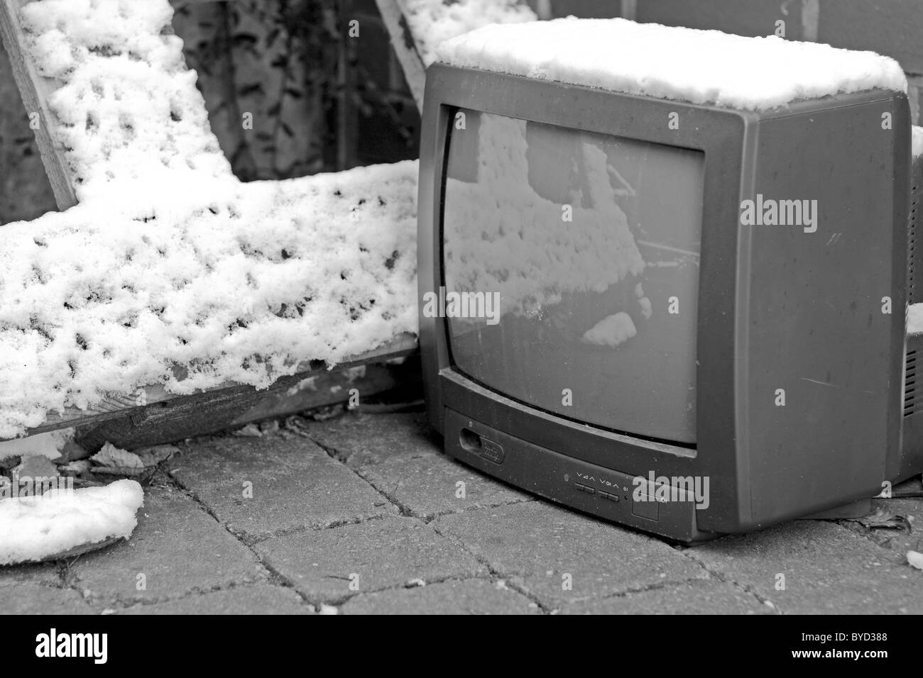 Un vecchio televisore portatile su una stradina innevata, gettate per rottami, accanto a una tavolozza di legno. Foto Stock