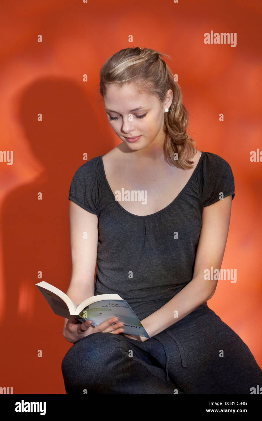 Giovane donna seduta su uno sgabello e la lettura di un libro Foto Stock