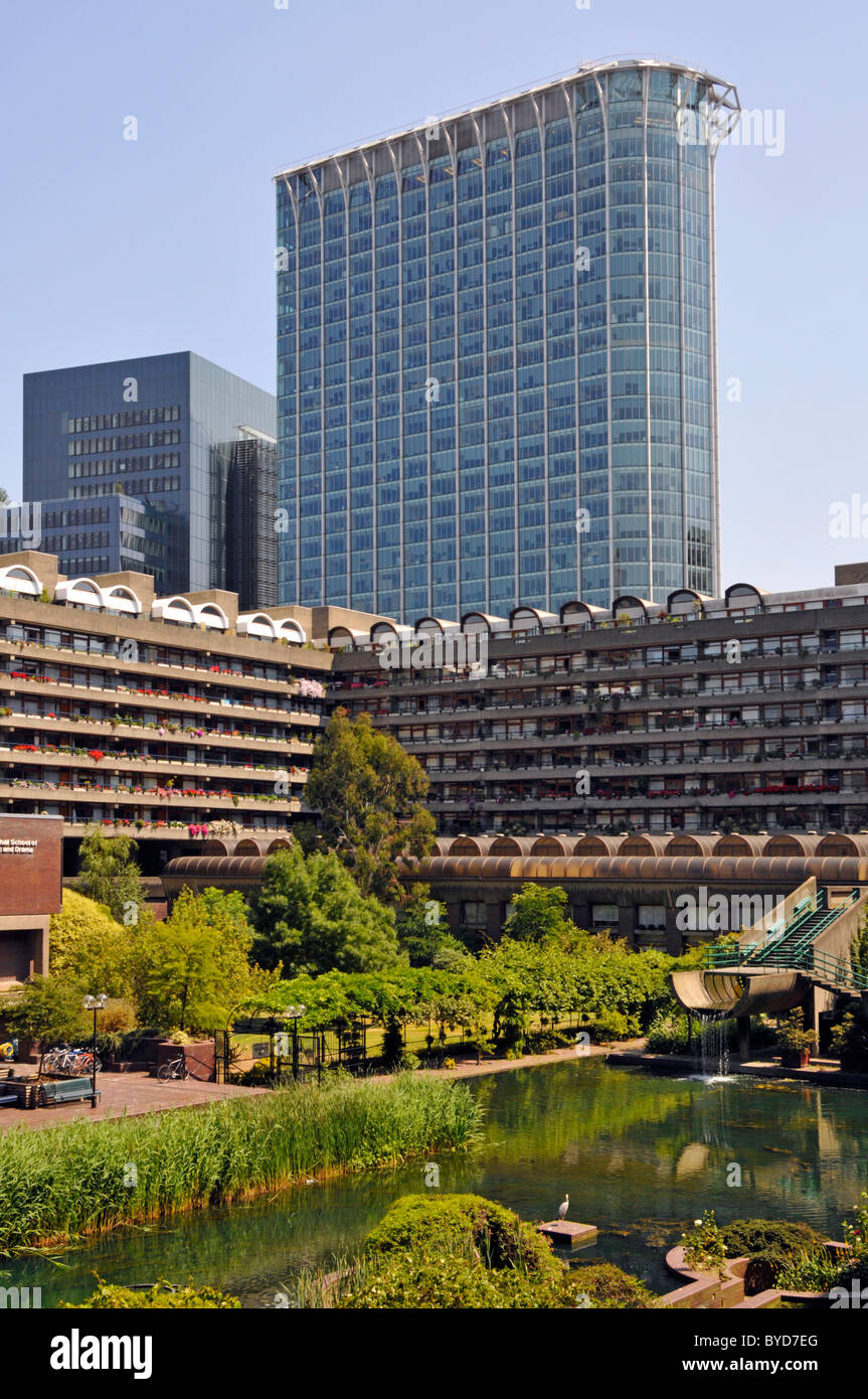 City of London Barbican acqua giardino intorno casa appartamento in blocchi di appartamenti e alto della torre di uffici blocco al di là nel paesaggio urbano England Regno Unito Foto Stock