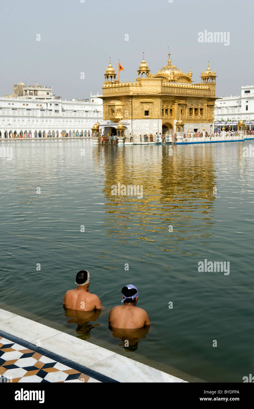 Il sikhismo, rituale lavaggio, due i credenti della religione Sikh prendendo un bagno rituale nel lago sacro tempio d'oro, Hari Mandir, Amritsar Foto Stock