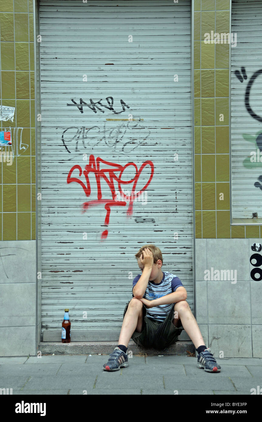 Lonely bambino di nove anni nella parte anteriore della chiusura di un business che è cosparso di graffiti, Germania, Europa Foto Stock