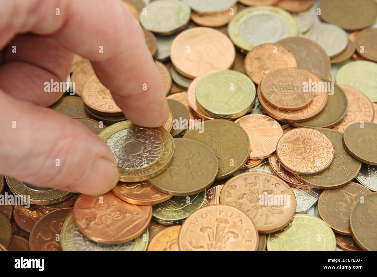 Un dito e il pollice il prelievo di una sterlina GBP 2 moneta da una ridda di monete Foto Stock