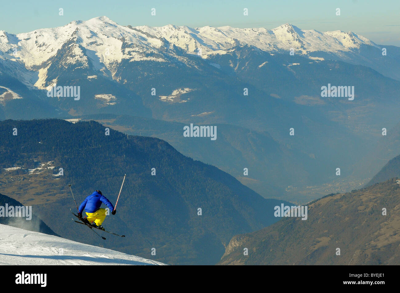 Uno sciatore salta fuori una cresta con una valle in background. Foto Stock