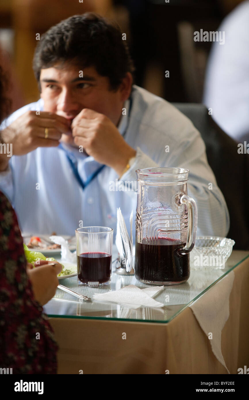 Un uomo peruviano ha il pranzo in un ristorante di Ayacucho. Sul tavolo è una brocca di Chicha Morada, bevanda fatta da granturco granturco. Foto Stock