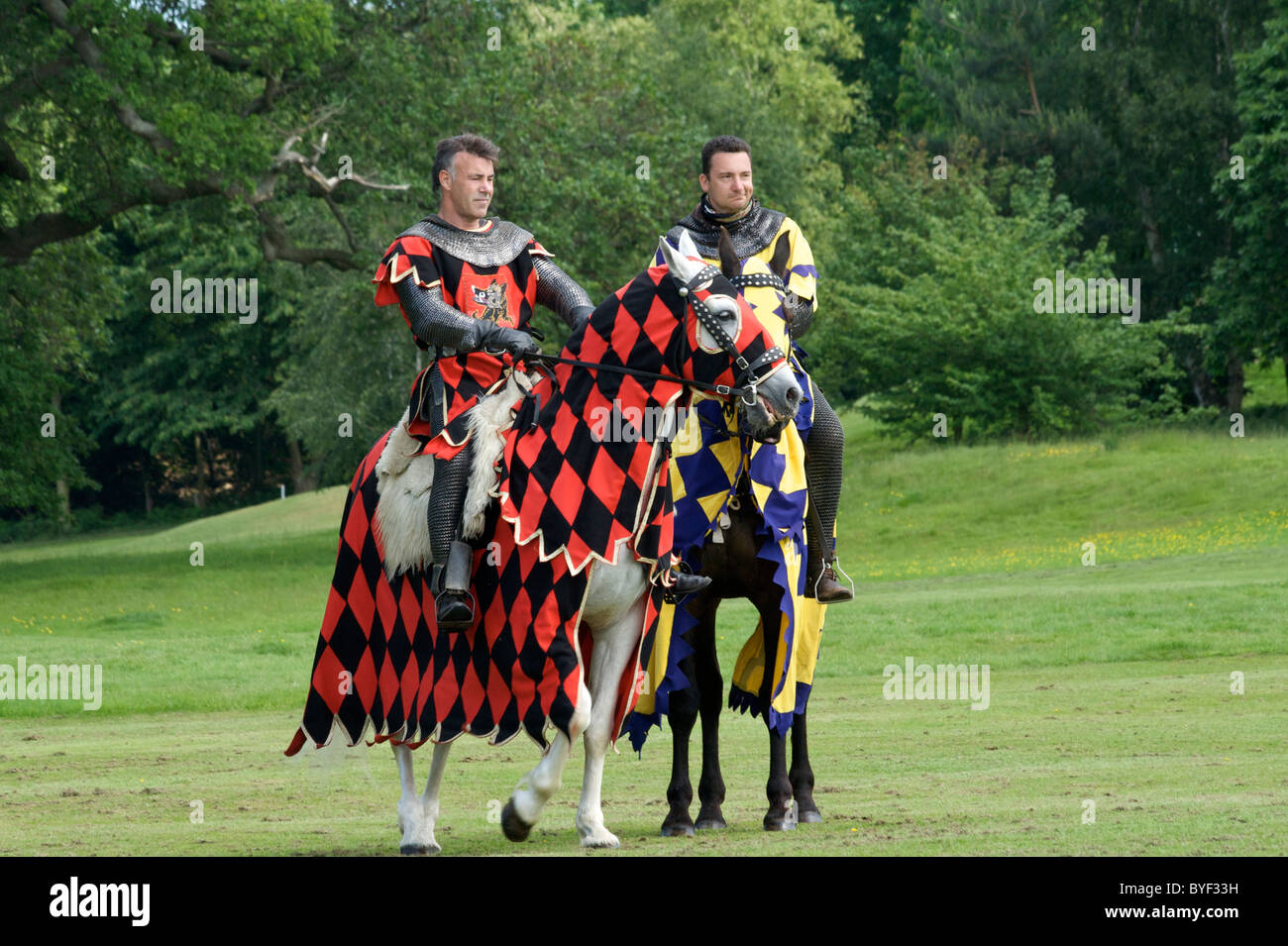 Giostra cavalieri a cavallo (destrieri) indossare catena-mail e Royal colori, al Castello di Leeds Foto Stock