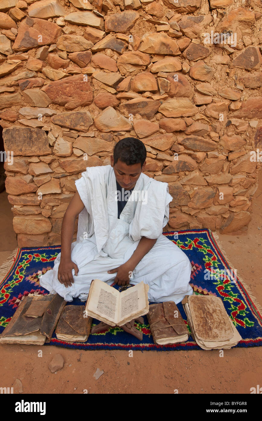 Arab ragazzo lettura testi coranici da antichi libri in Chinguetti, Mauritania, sede di una delle più antiche del mondo moschee Foto Stock