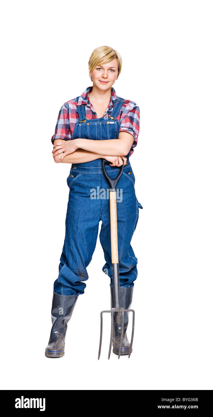Donna con forcone in piedi contro uno sfondo bianco, sorridente, ritratto Foto Stock