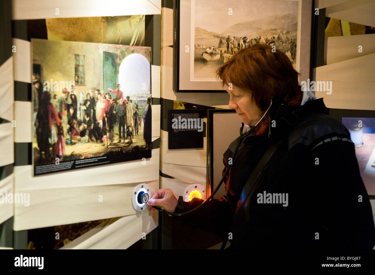 Tourist indossando 'stethoscope' le cuffie / cuffie audio guida guardando un display. Florence Nightingale Museum. Londra. Regno Unito. Foto Stock