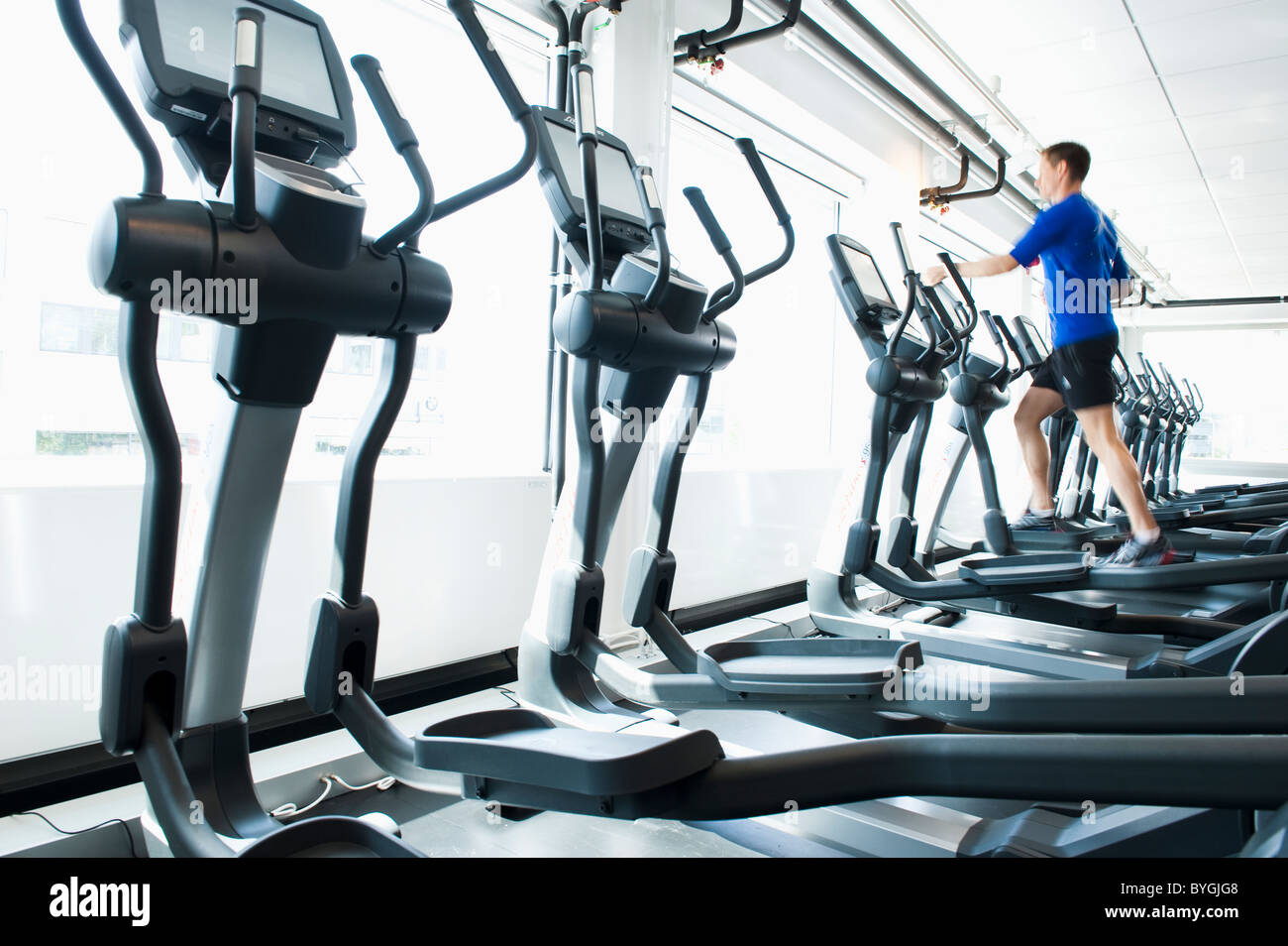 Uomo in esecuzione sulla macchina ginnica in palestra Foto Stock