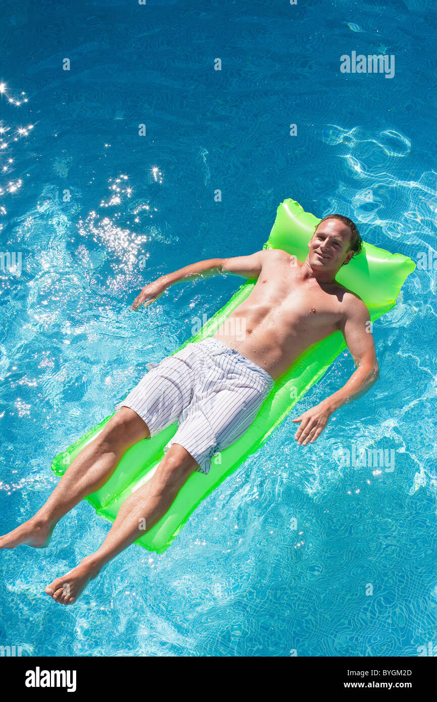 Uomo sulla zattera gonfiabile in piscina Foto Stock