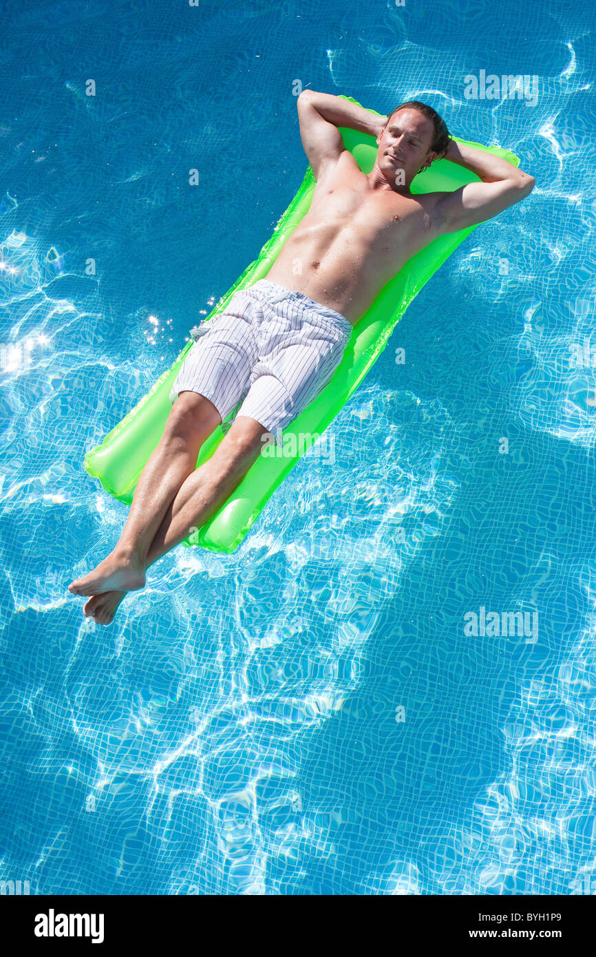 Uomo sulla zattera gonfiabile in piscina Foto Stock