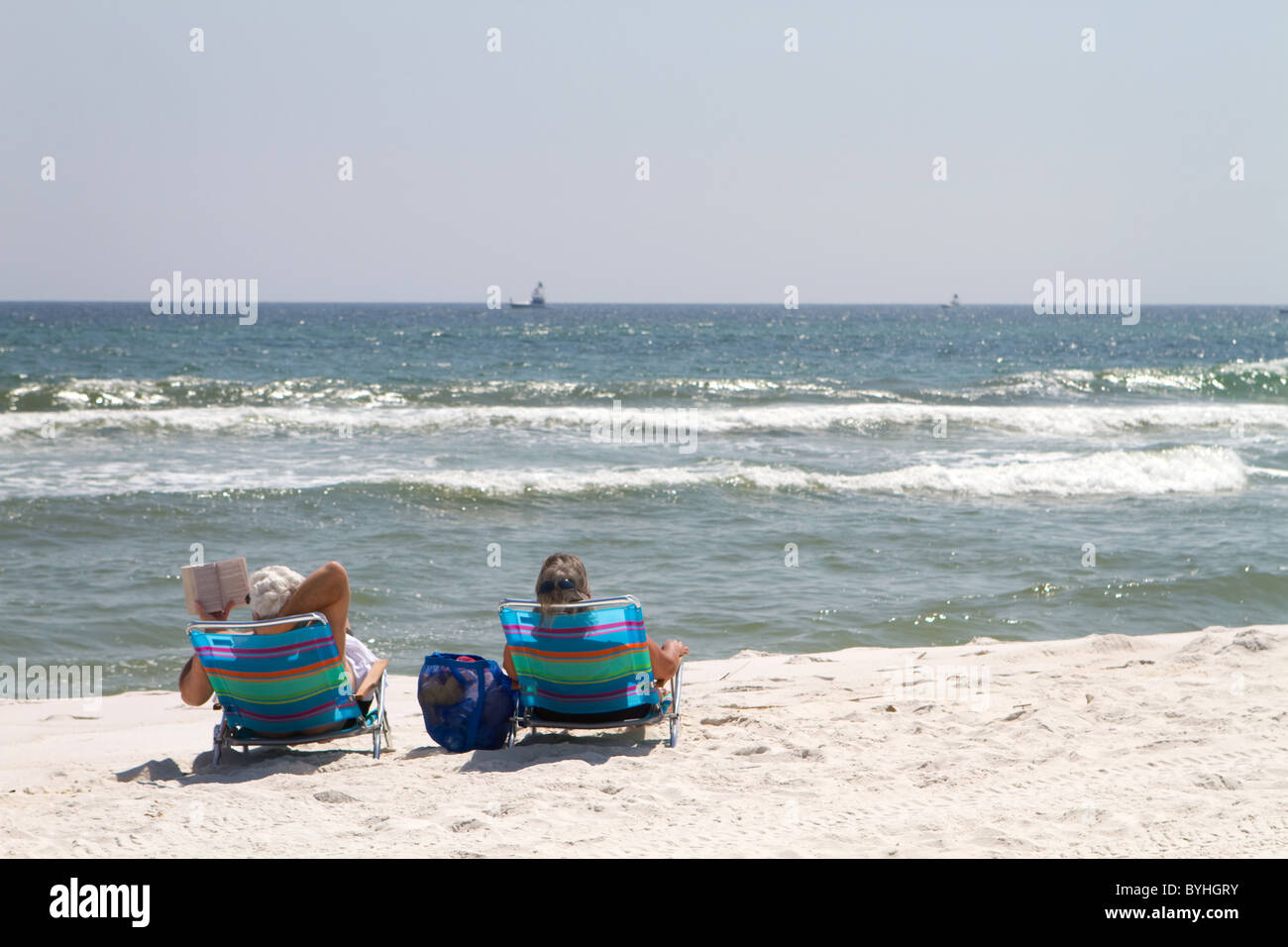 Due turisti relax in riva al mare seduti sulla spiaggia strippato charis in una giornata di sole. Foto Stock