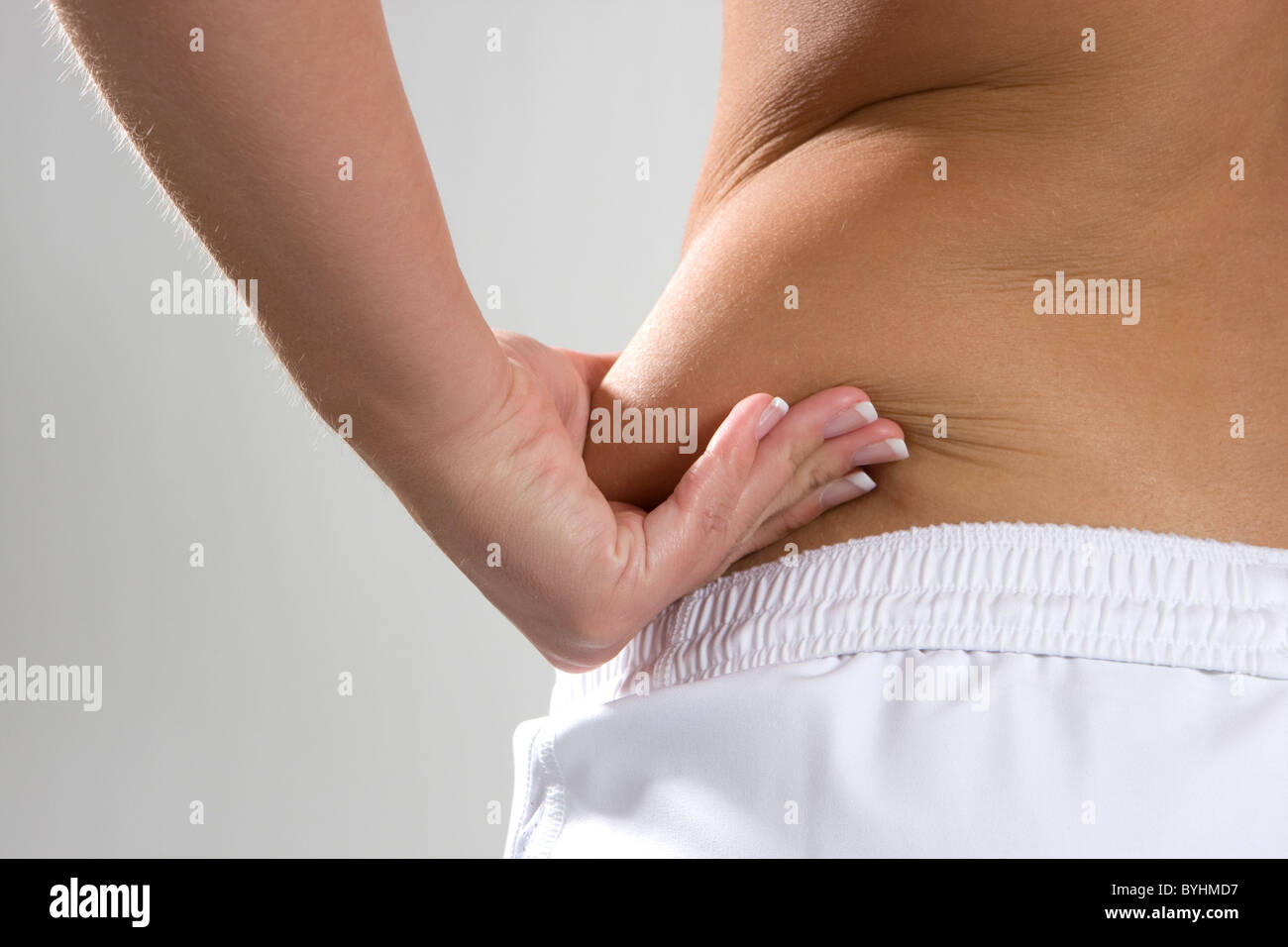 Giovane donna pizzichi del grasso sul lato della sua vita per mostrare il flab. Foto Stock