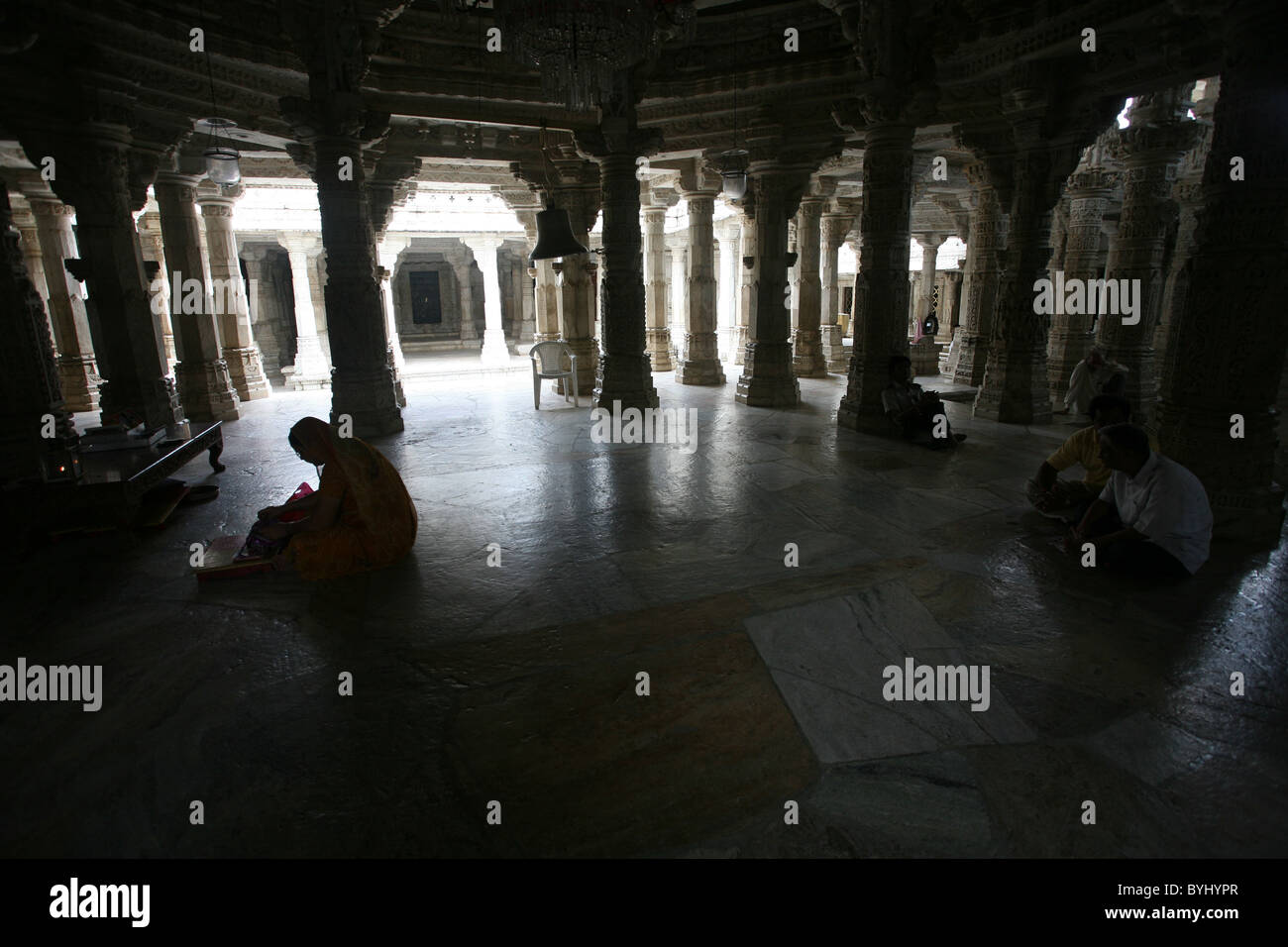 I devoti seduti in preghiera all interno di marmo di Jain Adishwar Chaumukha Mandir Ranakpur Temple, Rajasthan Foto Stock