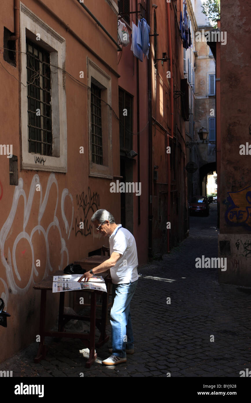 Un uomo leggendo un giornale in strada, Roma, Italia Foto Stock