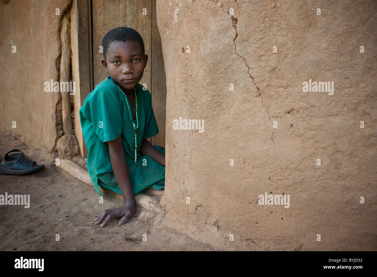 Un bambino si siede alla porta della sua casa di Masaka Uganda Foto Stock