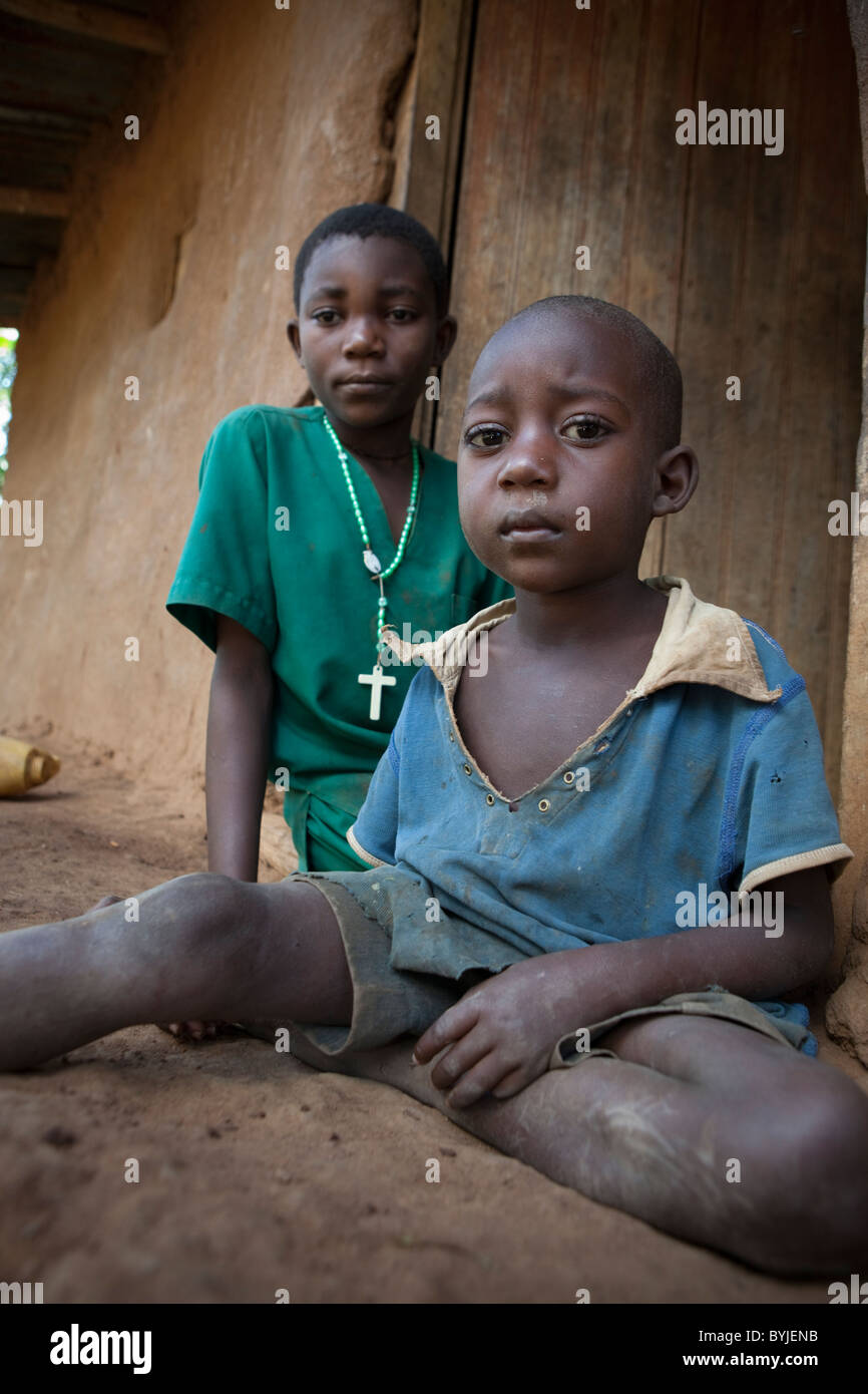 I bambini seduti fuori la porta della loro casa di fango nelle zone rurali a Masaka, Uganda, Africa orientale. Foto Stock