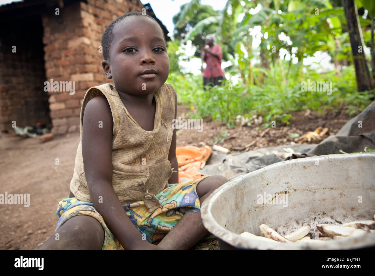 Un ragazzo si siede da una pentola piena di banane nelle zone rurali a Masaka, Uganda, Africa orientale. Foto Stock