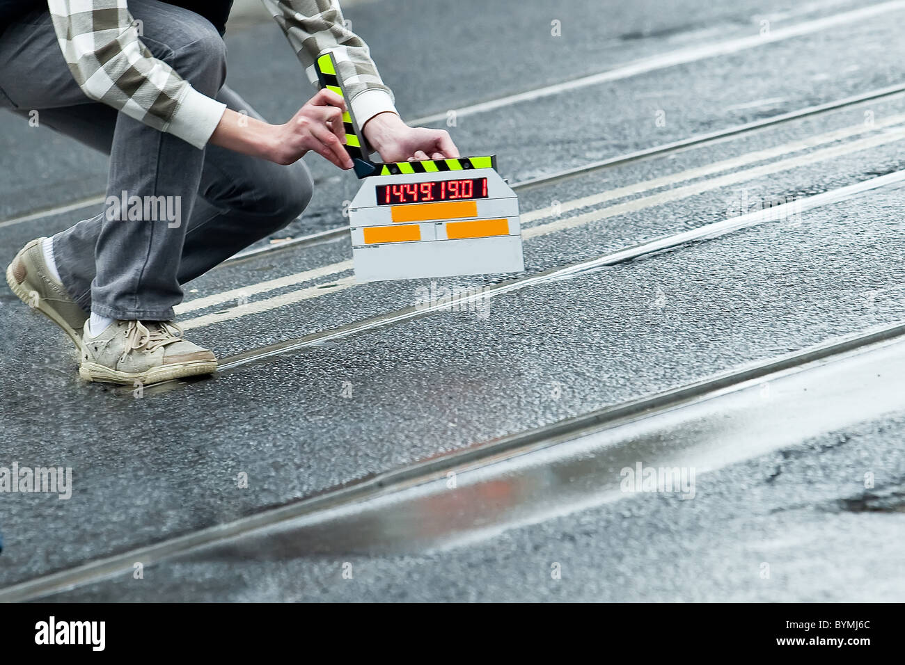 Realizzazione del film e ardesia tenendo da parte di un uomo sulla strada bagnata Foto Stock