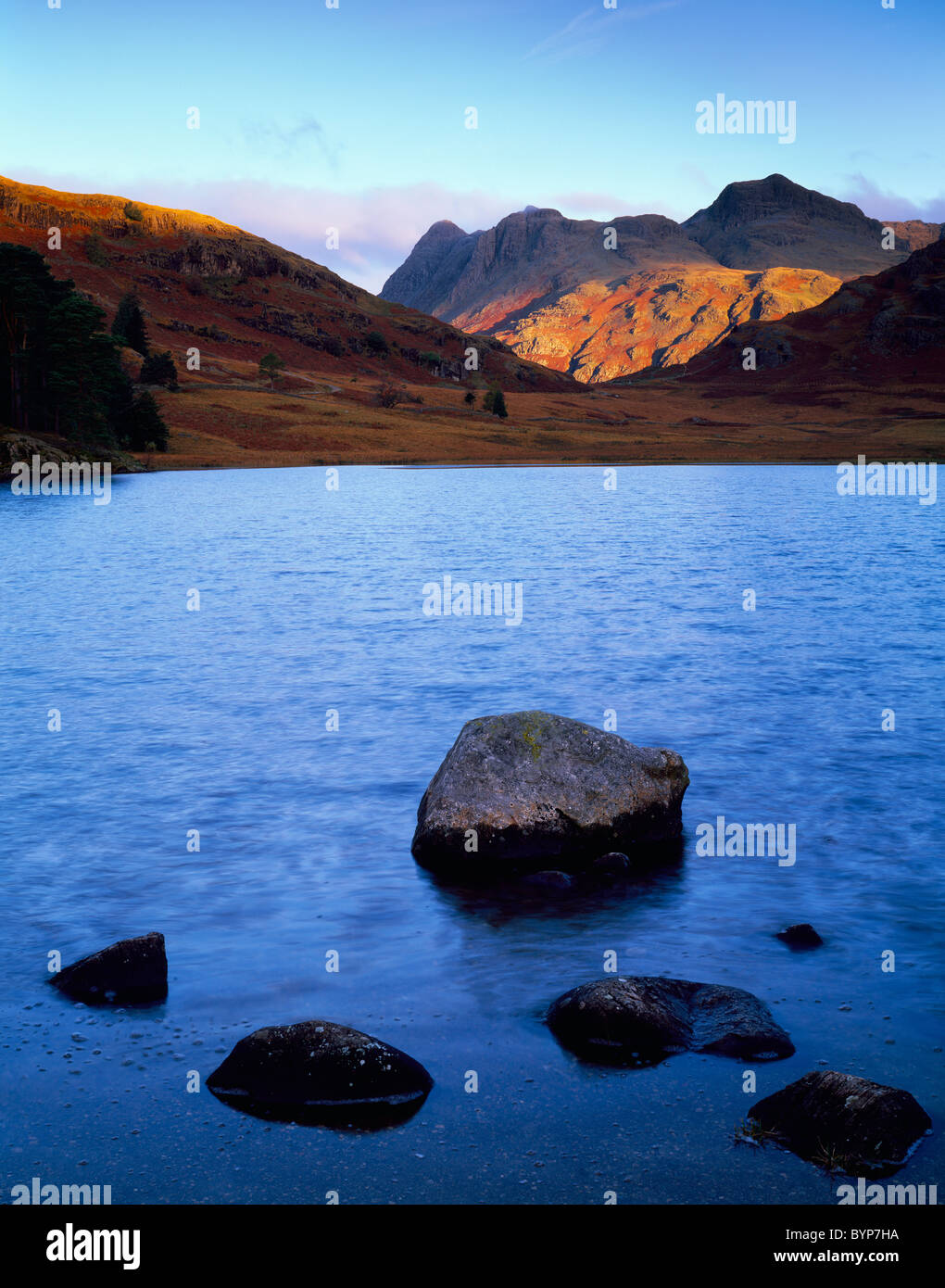 Dawn luce del sole sulle Langdale Pikes vista sulle acque di Blea Tarn nel Lake District National Park. Cumbria, Inghilterra. Foto Stock