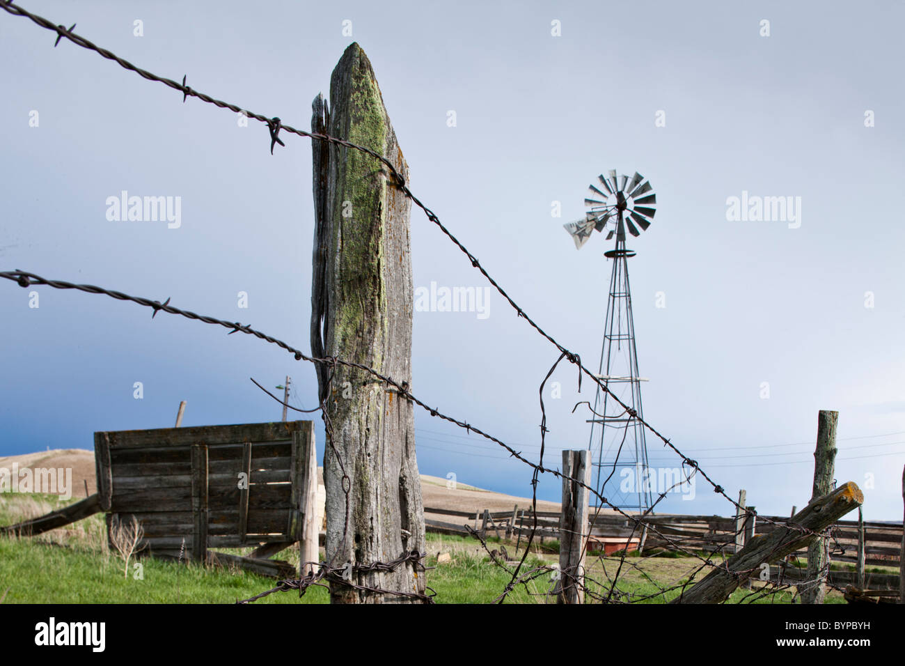 Stati Uniti d'America, North Dakota, Watford City, Windmill arrugginiti e filo spinato a azienda abbandonata sito su prairie Foto Stock