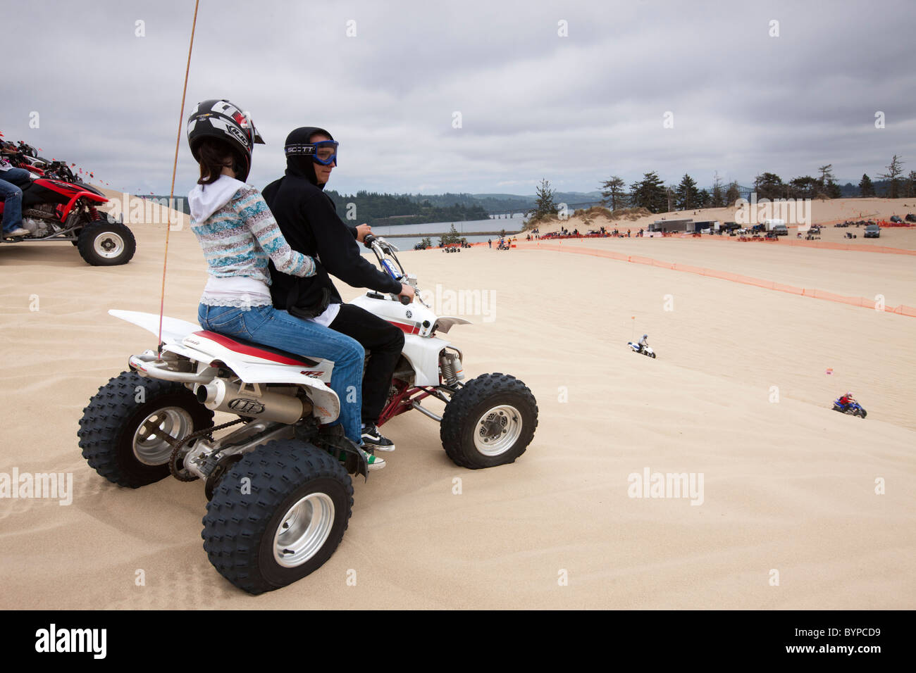 Stati Uniti d'America, Oregon, North Bend, coppia giovane si siede in cima ATV su alta cresta di sabbia a Oregon Dunes National Recreation Area Foto Stock